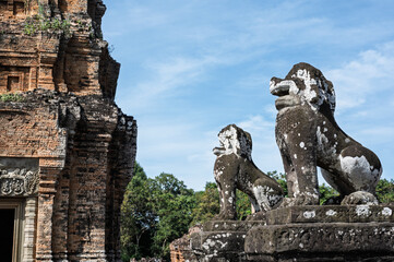 Obraz premium Close up of two weathered stone lion statues guarding entrance to ancient temple ruins in angkor archaeological park siem reap