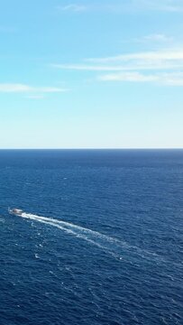 Wide view of the deep blue sea under a clear sky with a boat wake, captured near Capo di Conca on the Amalfi Coast, Italy.