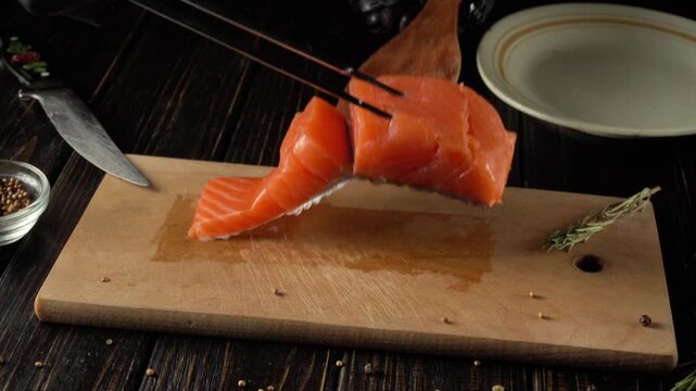 Salmon fillet being sliced and lifted from a wooden cutting board with kitchen utensils, showcasing the preparation process in a rustic kitchen setting
