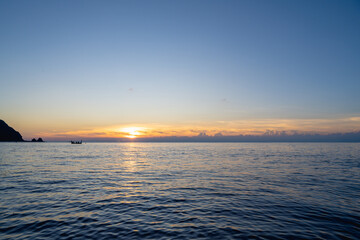 Obraz premium Lanyu, Taiwan - March 2026: Silhouette of a traditional Tao plank boat at sunrise over the calm Pacific Ocean, Taiwan.