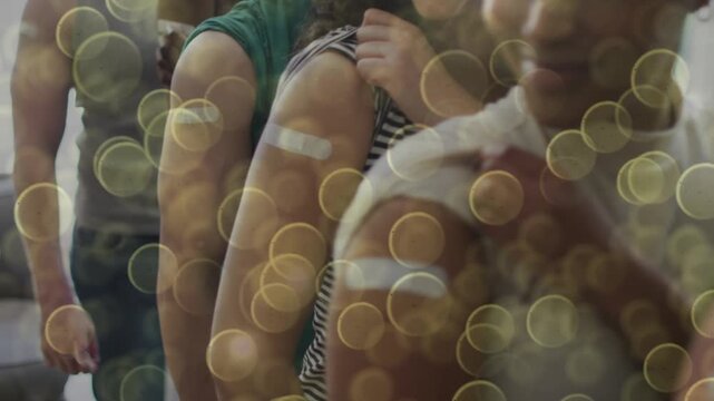 Animation of light spots over diverse people showing arms with bandage