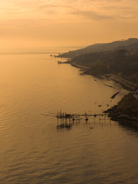Aerial view of the golden light kisses the Trabocchi coast, casting long shadows over the fishing platforms and the Adriatic Sea, San Vito Chietino, Abruzzo, Italy.