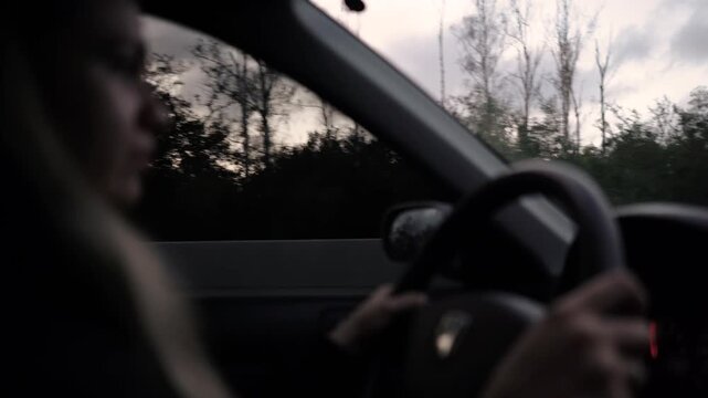 A driver is driving along a highway in the evening. A traveler, using a navigator for assistance, is heading into the city.