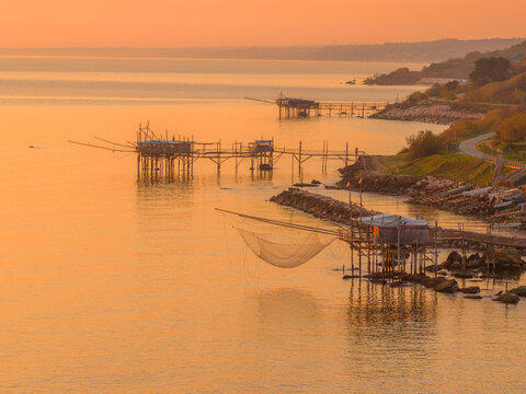 Aerial view of the trabucchi standing as silent sentinels amidst the sea, bathed in the warm glow of the setting sun, San Vito Chietino, Abruzzo, Italy.
