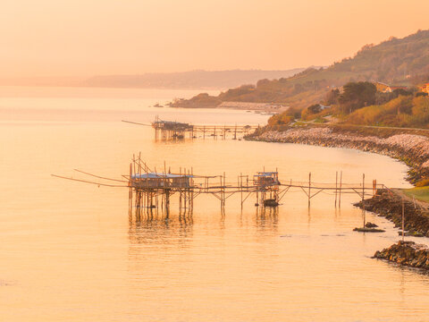 Aerial view of the golden Adriatic Sea reflecting the soft light around the Trabocchi Turchino, ancient fishing platforms, San Vito Chietino, Abruzzo, Italy.