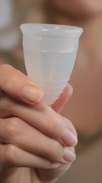 Female Presenting Silicone Menstrual Cup In Detail. Close Perspective Of Woman Holding Silicone Menstrual Product. Woman Demonstrating Silicone Menstrual Cup With Detailed Close View Of Device