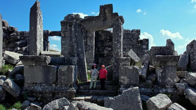 Two young people exploring ancient stone gateway ruins at Termessos Ancient City in Antalya, Turkey. A scenic blend of history, nature and travel, highlighting cultural heritage and discovery.