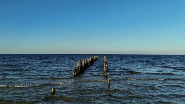 Aerial Shot of Sea Waves Around Wooden Posts at Sunset Light