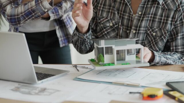 Engineers, architects, and technicians are analyzing structural design drafts in meetings with tabletop blueprints and discussing the project collaboratively in office meetings.