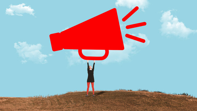 Woman standing on hill holding oversized megaphone shape against blue sky background. Concept of public announcement, marketing communication, brand promotion and loud message delivery.