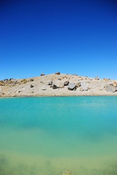 View of a rocky lakeshore across an Emerald lake, Tongariro Alpine Crossing, Tongariro National Park, Waikato region, North Island, New Zealand