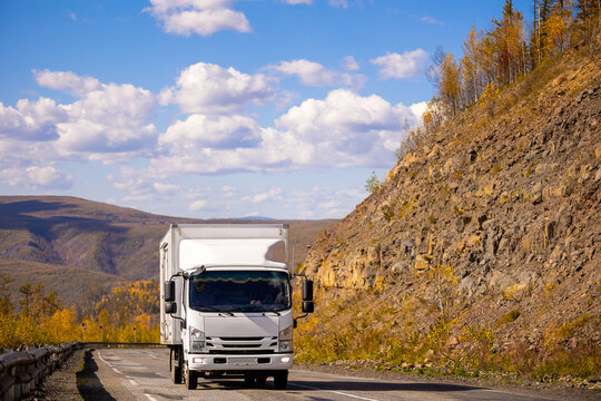 White japanese van moving by a mountain road