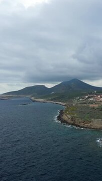 Moody seascape with rugged cliffs and mountains along the coast near Methoni, Greece, under a cloudy sky.
