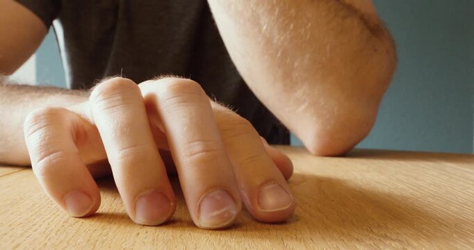 Close-up of a man tapping his fingers on a table, expressing nervousness, impatience, or waiting.