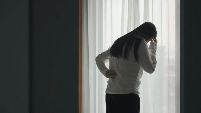 Tired young woman experiencing discomfort in lower back pain, cervical spondylosis, muscle weakness. Female holds lower back and can barely stand up affect daily activities, indicating pain or strain
