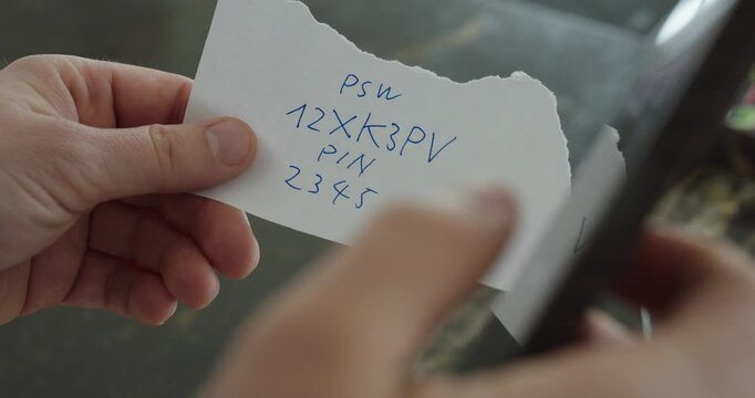 Close-up of a person typing a password and PIN into a smartphone using a handwritten note.