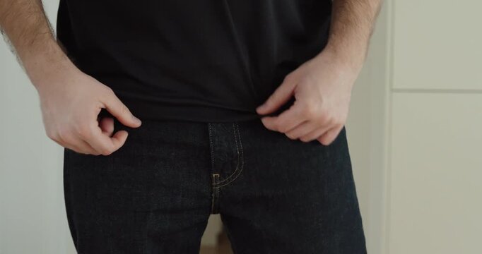 Close-up of a man closing the zipper of his pants while getting dressed.