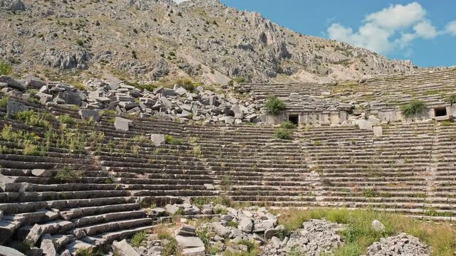 Wide angle view of the ancient amphitheater carved into the mountainside at Termessos Ancient City in Antalya, Turkey. Historic architecture surrounded by nature and rich cultural heritage.