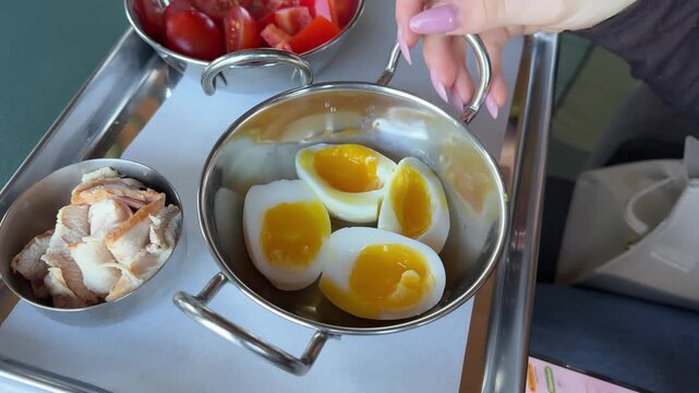 Close up of person holding soft-boiled egg with runny yolk partially turned into other half of white shell over plate, showing texture and gentle handling of fragile egg during food .