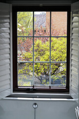 Fototapeta premium Spring Courtyard View Through Traditional Window with Blooming Trees