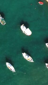 Aerial view of small fishing boats floating on clear turquoise water near the coast of Koroni, Greece. Peaceful maritime scene with vibrant colors and calm sea.