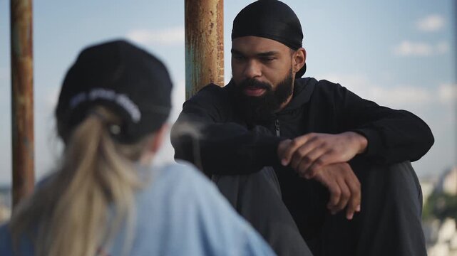 Young Black man in a durag talking with girlfriend while staying on rooftop