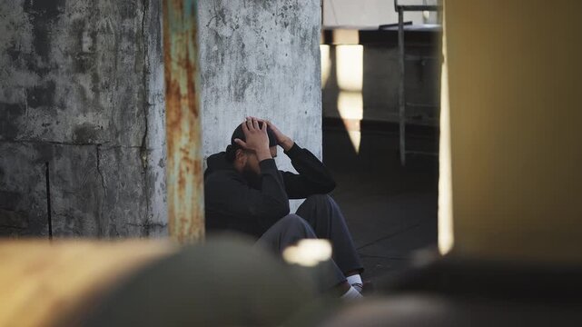 Depressed African American in a hoodie sitting alone on empty rooftop, stress