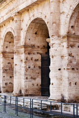 Naklejka premium Old stone wall with holes near metal gate in historic city area