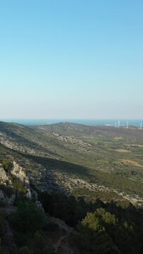 Wide view of rugged hills covered in greenery with the sea visible on the horizon under a clear blue sky. Peaceful natural landscape, possibly near the English Channel.
