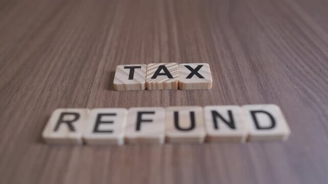 "Cinematic focus shifts between the wooden words TAX and REFUND on a rustic background."