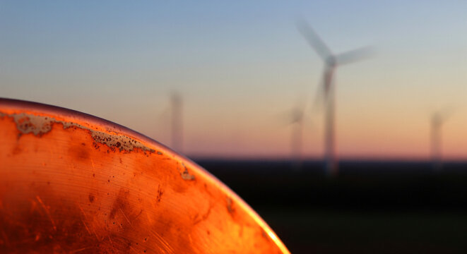 Copper cathodes are shown near wind turbines in a renewable energy site during sunset