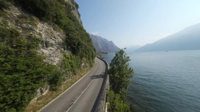 Europe Italy Lake Garda FPV flight near street and Lake sunrise blue sky 60fps 4K slow motion possible, old street , mountains