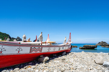 Obraz premium Lanyu, Taiwan - June 24, 2025: Traditional Tao plank boats on the shore with volcanic bay view.
