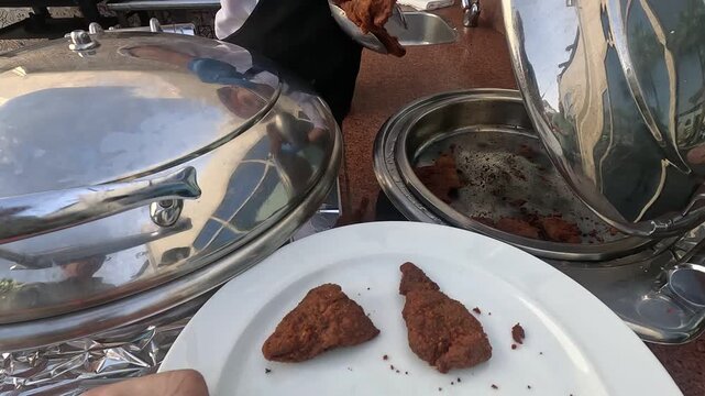 Cook serves fried schnitzel at resort hotel buffet. Man preparing breaded meat in deep fryer for dinner service. Professional culinary process at egypt hotel.