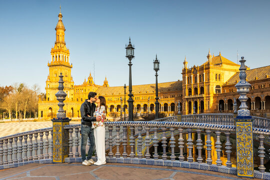 Travel, tourism: Couple kissing on bridge at Plaza de Espa&ntilde;a, Seville, Spain. Romantic moment in a historic landmark.