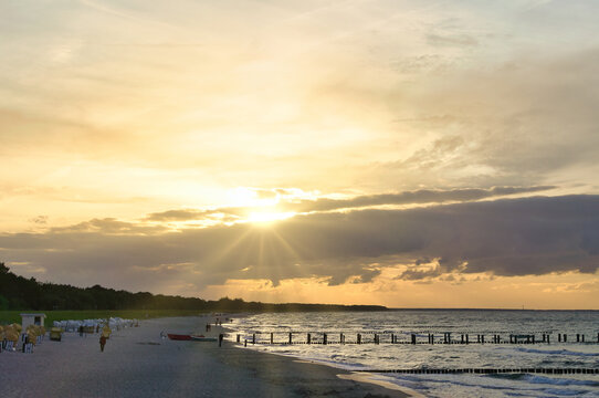 Beautiful sunset at the Baltic Sea beach with beach chairs and wooden groynes