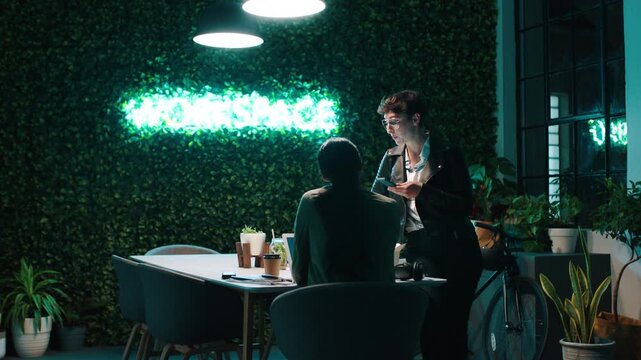 Night, people and discussion in office with laptop, phone or planning for digital marketing project. Late, women and talk in workplace with computer, collaboration and deadline for online advertising