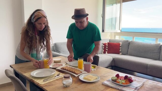 Pareja colocando caf&eacute; y zumo sobre la mesa