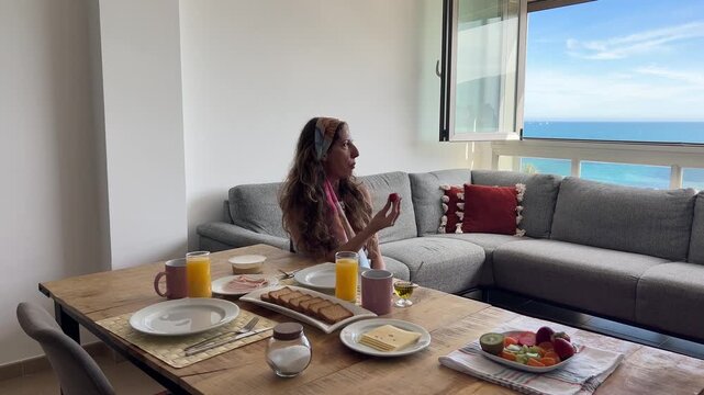 Mujer mordiendo una fresa mirando al mar