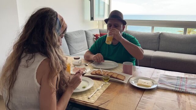 Pareja disfrutando desayuno mediterr&aacute;neo con vistas al mar