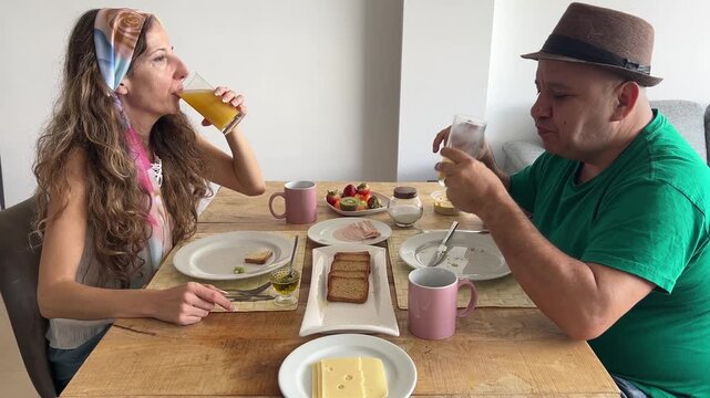 Pareja brindando con zumo de naranja y sonriendo