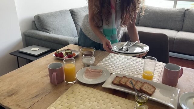 &Oacute;rbita sobre mujer recogiendo la mesa tras desayuno