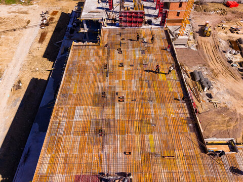 Construction workers placing steel rebar for concrete slab at a building site in the daytime in a city under development