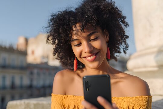 Woman smiling while looking at a firefly app on her phone outdoors on a sunny day