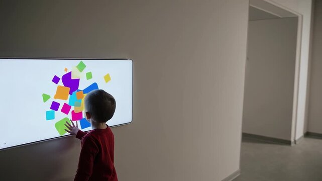 Young learner interacting with bright digital touchscreen, exploring colorful educational interface while developing tech savvy skills in contemporary classroom environment