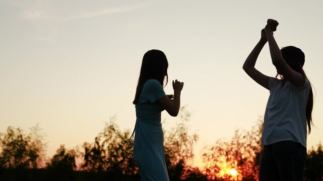 Happy teenagers dancing in park at sunrise. Beautiful girls dancing outdoor party. Happy people dancing outdoors. Slow motion. Cheerful girls having fun listening music. Friends throwing festive disco