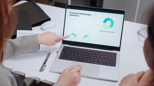 Close up of businesswomen analyzing customer satisfaction data and charts on laptop screen in the office.