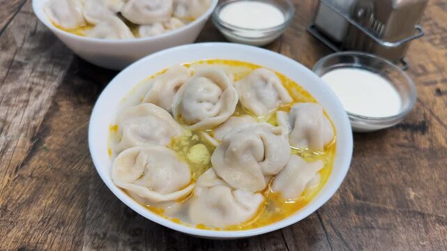 Homemade dumplings close-up in a bowl served with broth and sour cream. High quality 4k footage