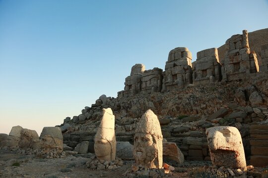Close view of the iconic headless statues and massive stone structures atop Mount Nemrut, remnants of ancient royal tomb complex standing against the dramatic mountain landscape.