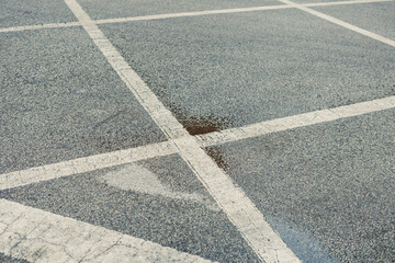 Fototapeta premium Rainwater collects in a parking lot with parking lines visible on the concrete surface during daytime